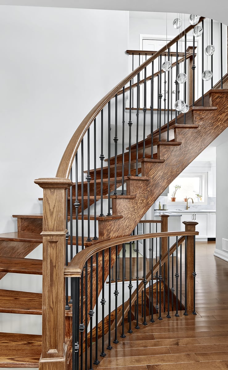 Curved wooden staircase to second storey in Markham home renovation by Master Edge Homes