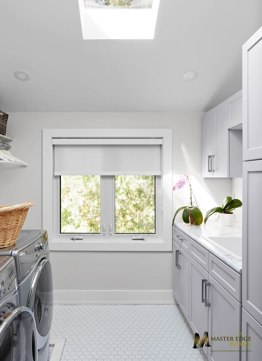 Custom laundry room renovation with white shaker cabinets and skylight