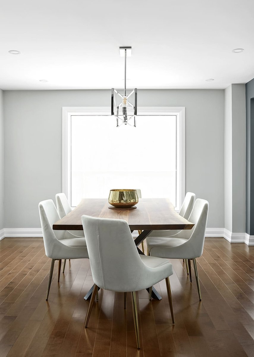 Five white chairs around rectangular dining room table in front of window in Markham home renovation by Master Edge Homes