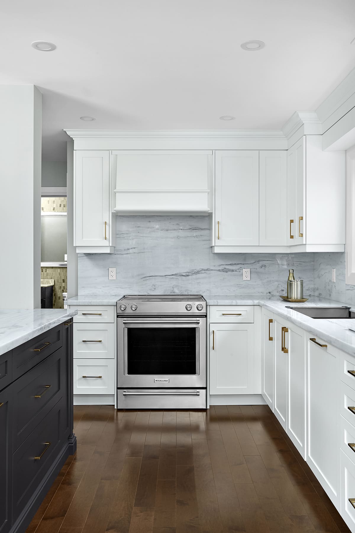 Stainless steel oven and stone backsplash behind white cabinets in Markham home renovation