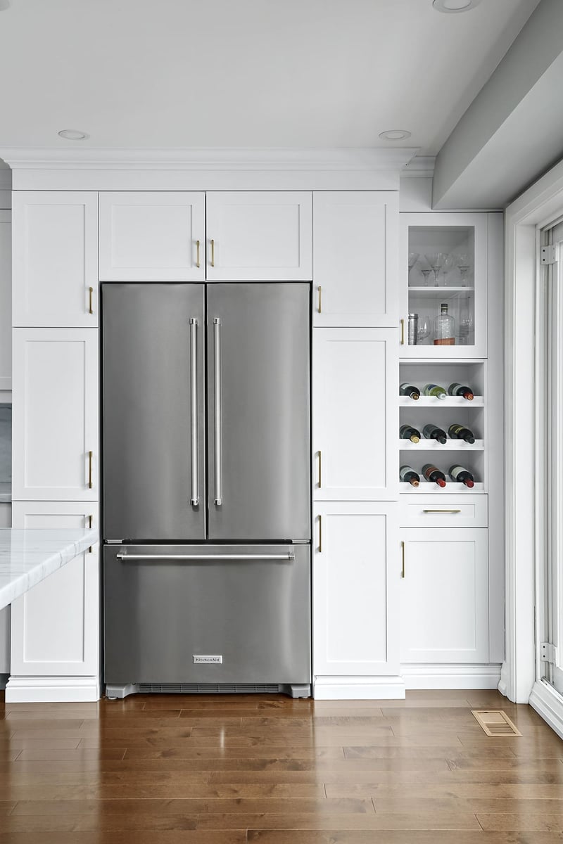 White cabinets surrounding stainless steel refrigerator with built-in wine storage in Markham home renovation