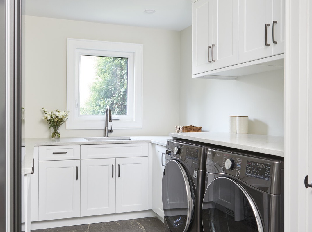 Laundry room with cabinetry and sink in Markham home renovation by Master Edge Homes